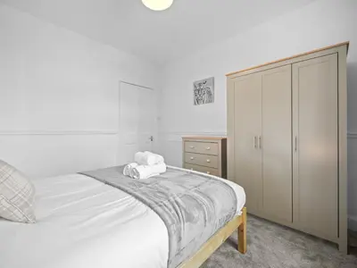 a white bedroom with a bed and a dresser at Whiteside 3 Bedroom Apartment - Bathgate in Bathgate
