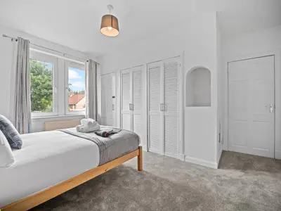 a white bedroom with a bed and a window at Mollison 2 Bedroom Apartment - Harthill in Harthill