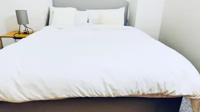 a white bed in a room with a lamp at City Central Stay in Glasgow