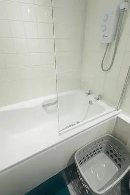 a bathroom with a tub with a shower and a sink at City Central Stay in Glasgow