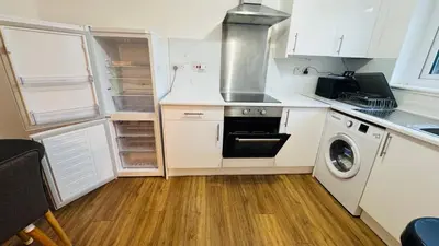 a kitchen with white cabinets and a washer and dryer at City Central Stay in Glasgow