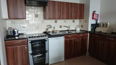 a kitchen with wooden cabinets and a white stove top oven at Kings Arms Holiday Apartments in Oban