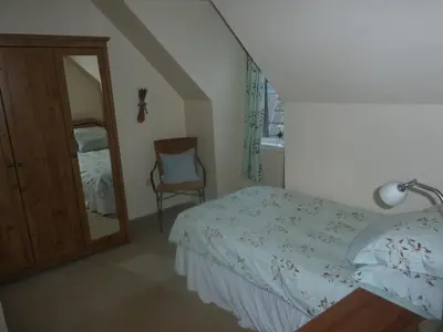 a bedroom with a bed and a mirror and a chair at Kings Arms Holiday Apartments in Oban