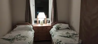 two beds in a room with a window at Kings Arms Holiday Apartments in Oban