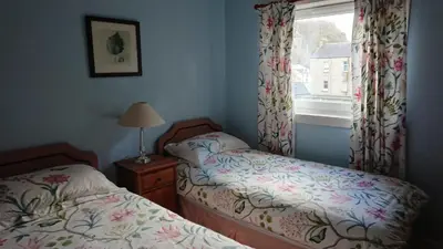 a bedroom with two twin beds and a window at Kings Arms Holiday Apartments in Oban