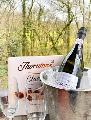 a bottle of wine in a bucket next to glasses at Blair snug hut 2 in Kelty