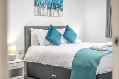 a bedroom with a bed with blue and white pillows at City Centre Apartment in Dunfermline