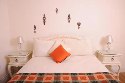 a bed with an orange pillow and two night stands at Llygad yr Haul in Moffat