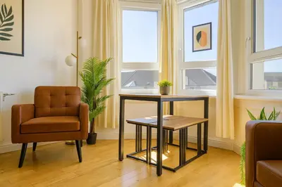 a living room with a chair and a table at Walk to Hydro and SEC Modern 3BR Free Parking in Glasgow