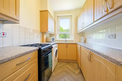 a kitchen with wooden cabinets and a stove top oven at Walk to Hydro and SEC Modern 3BR Free Parking in Glasgow