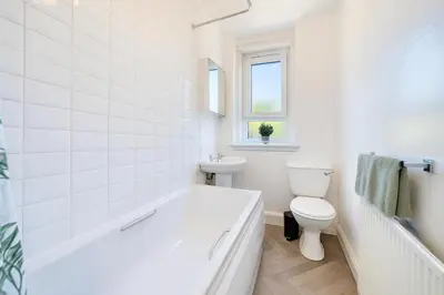a white bathroom with a tub and a toilet at Walk to Hydro and SEC Modern 3BR Free Parking in Glasgow