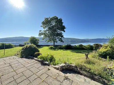 a view of a field with a tree and water at Avenue Cottage, Inveraray in Inveraray