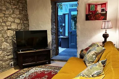 a living room with a yellow couch and a flat screen tv at Old Schoolhouse in Inveraray