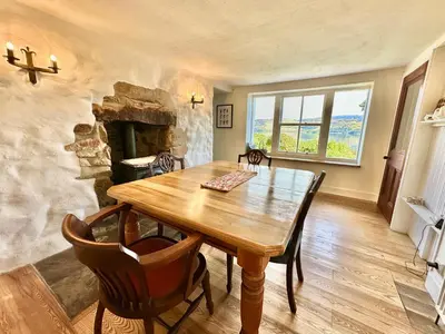a dining room with a wooden table and a stone fireplace at Old Schoolhouse in Inveraray
