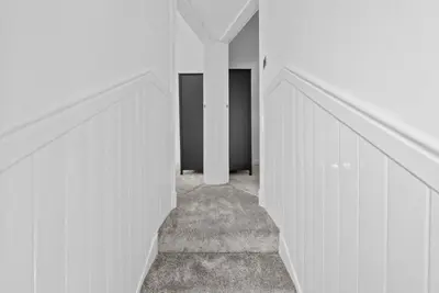 a hallway with white walls and stairs in a house at Kirkstyle Cottage in Coatbridge