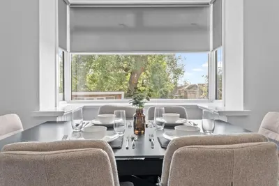 a dining room with a table with chairs and a window at Kirkstyle Cottage in Coatbridge