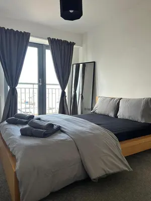 a bedroom with a large bed with a large window at Waterfront Spacious Flat in Edinburgh