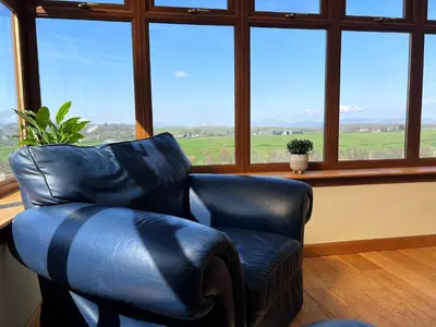 a leather chair in a room with a large window at Easter Auchencarroch Farm B&B in Balloch