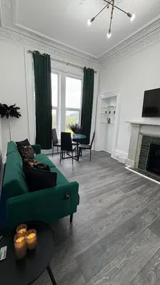 a living room with a green couch and a fireplace at Seaview apartment in Rothesay in Rothesay