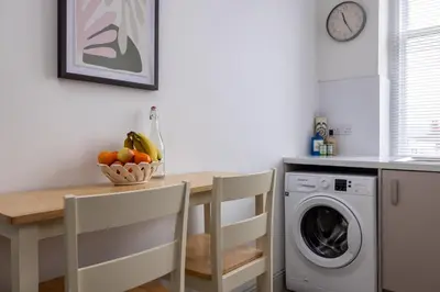 a kitchen with a table and a washing machine at Antonine Quarters in Grahamston