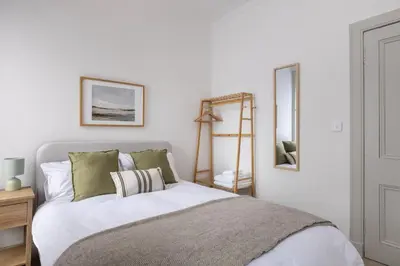 a bedroom with a bed with white sheets and green pillows at Antonine Quarters in Grahamston
