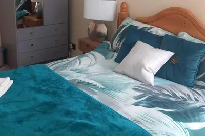 a bedroom with a bed with a blue and white comforter at gourock blissful apartment with 3 bedrooms in Gourock