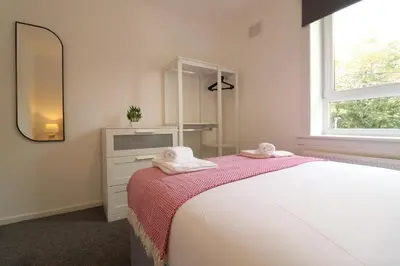 a bedroom with a bed with a mirror and a dresser at Signature - Hattrix View in Cumbernauld