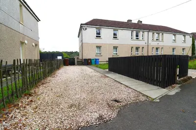 a fence in front of a house and a building at Signature - Hattrix View in Cumbernauld