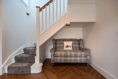 a chair with a cat pillow sitting under a staircase at Strathfillan Lodge in Crianlarich