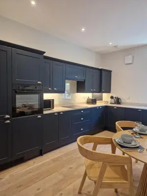 a kitchen with blue cabinets and a table with chairs at City Residence Free Parking in Stirling