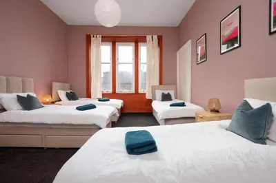 a bedroom with two beds with blue towels on them at Family and Group Stay 2BR by Park Sleeps 7 in Glasgow