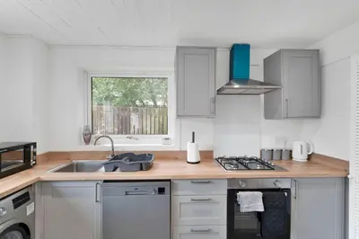 a kitchen with white cabinets and a sink and a window at 3BR Family House with Free Parking in West Lothian in Whitburn