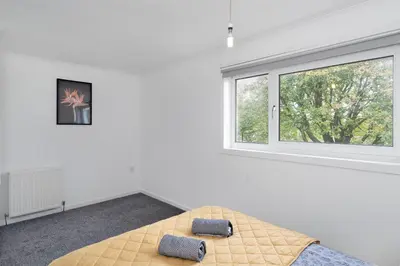 a white room with a bed and a window at 3BR Family House with Free Parking in West Lothian in Whitburn