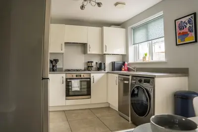 a kitchen with white cabinets and a washing machine at JustStay Glasgow - 3 Bedroom Luxury Villa with free parking in Bailleston