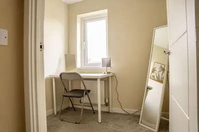 a chair in a room with a desk and a window at JustStay Glasgow - 3 Bedroom Luxury Villa with free parking in Bailleston