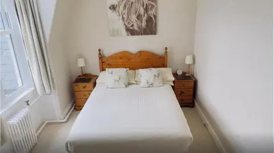 a bedroom with a bed with white sheets and pillows at Camus House, Lochside Guest House in Onich