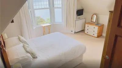 a bedroom with a white bed and a window at Camus House, Lochside Guest House in Onich