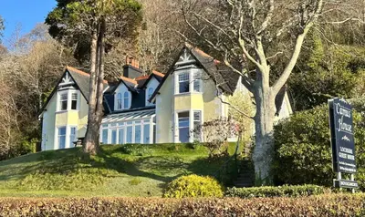 a large white house with a sign in front of it at Camus House, Lochside Guest House in Onich