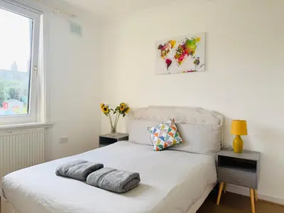 a white bed in a room with a window at Murrayfield Maindoor flat with Free parking and Great Public transports Link in Edinburgh