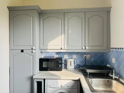 a kitchen with white cabinets and a sink and a microwave at Murrayfield Maindoor flat with Free parking and Great Public transports Link in Edinburgh
