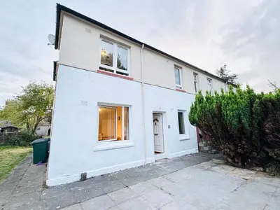 a white house with two windows and a hedge at Murrayfield Maindoor flat with Free parking and Great Public transports Link in Edinburgh