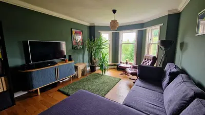 a living room with a couch and a flat screen tv at Modern Three-Bedroom Apartment in Leafy West End with Private Parking in Glasgow