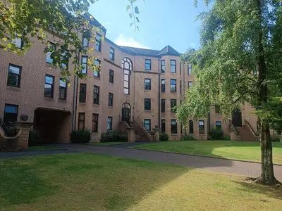 a large brick building with a tree in front of it at Modern Three-Bedroom Apartment in Leafy West End with Private Parking in Glasgow