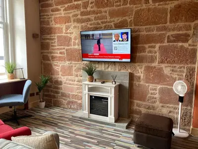 a living room with a fireplace and a tv on a brick wall at The Tartan Sheep in Kilmarnock