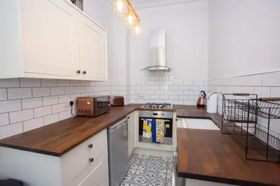 a kitchen with white cabinets and a stove top oven at 1 Bed Cosy Loch Lomond base in Bonhill