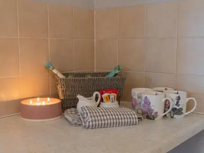 a counter with cups and a candle and a basket at 3 Bedroom Home, Peaceful Garden in Edinburgh