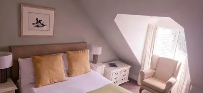 a bedroom with a bed and a chair and a window at The Bay Rooms at Glenisle Hotel in Lamlash