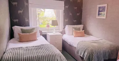 a bedroom with two beds and a window at The Bay Rooms at Glenisle Hotel in Lamlash