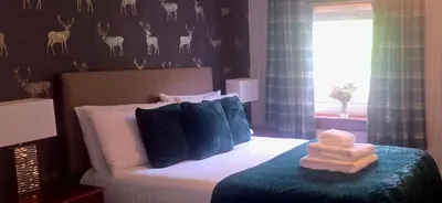 a bedroom with a bed with a teddy bear on it at The Bay Rooms at Glenisle Hotel in Lamlash