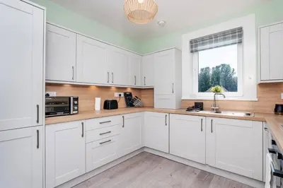 a white kitchen with white cabinets and a window at Ideal Work Stays 3BR Free Parking Sleeps 6 in Falkirk